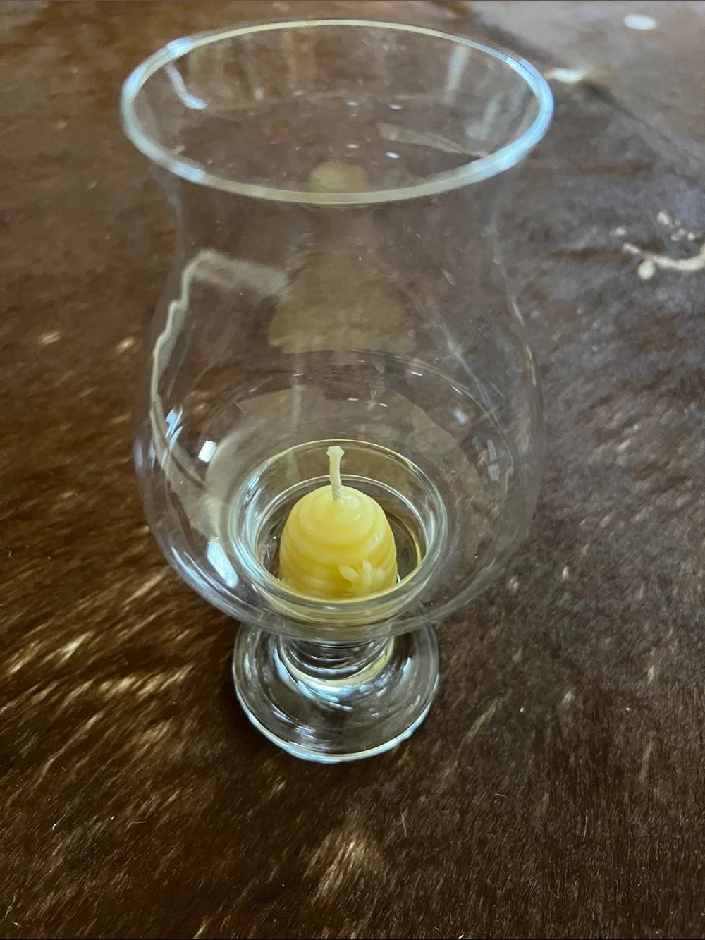 Clear glass hurricane candle holder features a pedestal base and a flared top